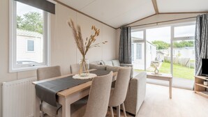 A modern living room with a dining area, large windows, and a view of a residential area. - Chalet in De Haan Near Sandy Beaches (De Haan)