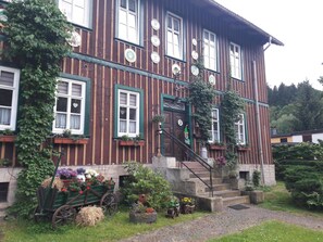A traditional wooden house with multiple windows, a front door, and a staircase leading to the entrance. - Apartment in Thale by Fishing River (Thale)