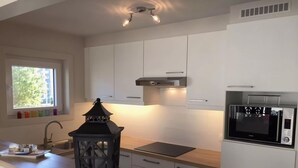 Una cocina moderna con armarios blancos, estufa negra y microondas.