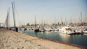 Un puerto deportivo con numerosos veleros amarrados a un muelle de piedra.