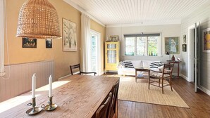 A dining area with a wooden table, chairs, and a hanging light fixture. - Attractive Apartment With Terrace-by Traum (Mellbystrand)