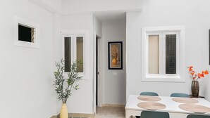 A dining area with a white table, green chairs, and a vase with flowers. - Beachhouse Gran Tarajal 3BR (Gran Tarajal)