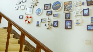 A staircase with wooden handrails and a wall decorated with framed pictures and nautical-themed wall art. - JIHUHENGXIANGBINGUAN (Shengsi)
