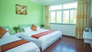 A hotel room with two beds, a painting on the wall, a window with curtains, and a bedside table with a plant. - JIHUHENGXIANGBINGUAN (Shengsi)