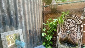 A small outdoor seating area with a table and chair, a decorative mirror, and a stone fountain. - Casa Flora, Brand-New Serene Guest House in Los Angeles with WiFi, AC (Los Angeles)