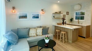 A modern living room with a sofa, a round coffee table, and a kitchen area with a bar. - Casa Flora, Brand-New Serene Guest House in Los Angeles with WiFi, AC (Los Angeles)