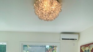A bedroom with a large bed, two bedside tables with lamps, a ceiling light fixture, a window with a view, and an air conditioning unit. - Casa Flora, Brand-New Serene Guest House in Los Angeles with WiFi, AC (Los Angeles)