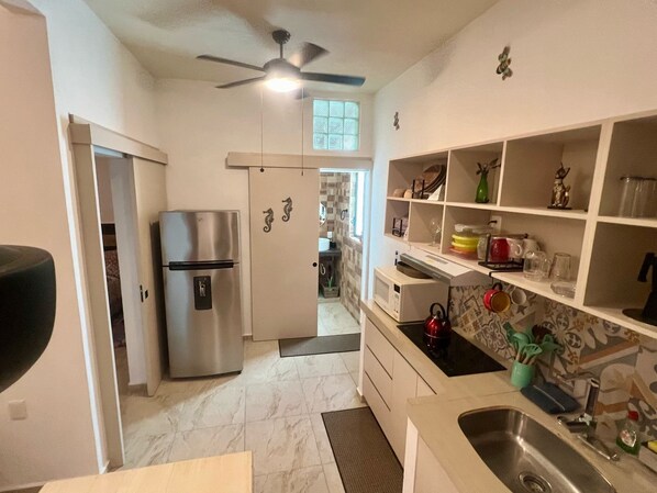 A compact kitchen with a refrigerator, microwave, and sink. - SWEET HOME steps from the beach & ferry to Isla Mujeres. With Pool & rooftop (Cancun)