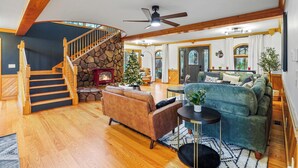 Un salon spacieux avec une cheminée en pierre, un escalier en bois et un coin salon confortable.