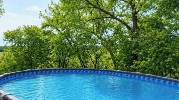 Ein klares, blaues Schwimmbecken, umgeben von einer Betonplattform, mit Bäumen im Hintergrund.
