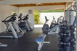 Un gimnasio con cintas de correr, bicicletas estáticas y máquinas de pesas.