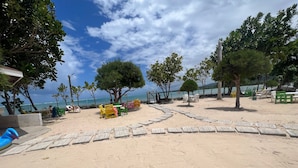 A beach with a paved walkway, seating areas, and trees. - Avant Family Villa (St. Ann's Bay)