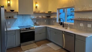 Une cuisine moderne avec des meubles gris, une cuisinière en acier inoxydable et une fenêtre donnant sur l’extérieur.