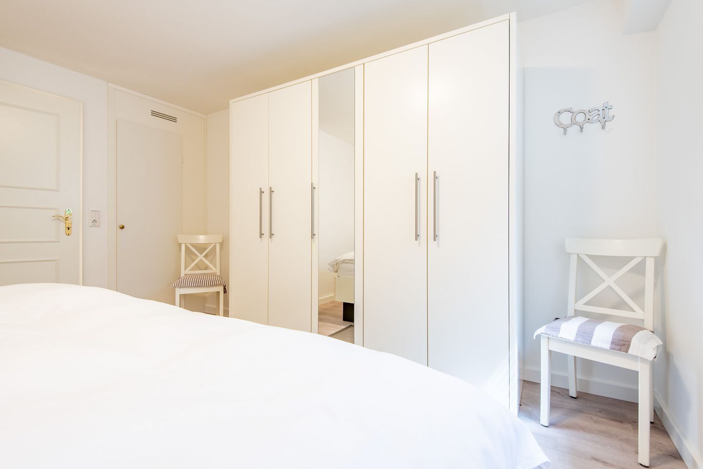 Ein Schlafzimmer mit einem großen Bett, einem Kleiderschrank, einem Sessel und einem kleinen Tisch.