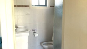 A small, compact bathroom with a window, a sink, a toilet, and a trash bin. - Cabin 5 - 2 single beds and ensuite. Access to all amenities (O'Connell)