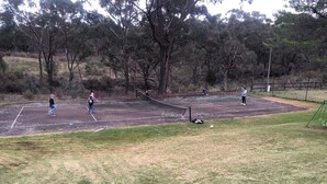 A tennis court with players, surrounded by trees and a grassy area. - Cabin 5 - 2 single beds and ensuite. Access to all amenities (O'Connell)