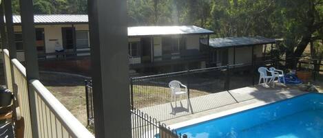Een zwembad met een omheind terras, omringd door een gebouw met een plat dak en een overdekte patio.
