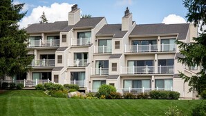 Un edificio residencial de varios pisos con balcones y un césped bien cuidado.