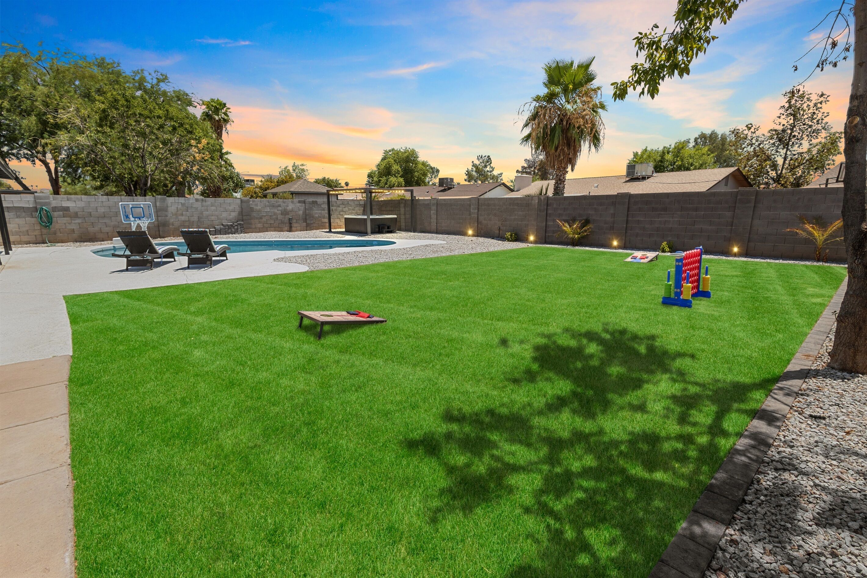 Un jardin avec une piscine, deux chaises longues, une petite table et un espace de jeux avec des blocs de construction colorés.