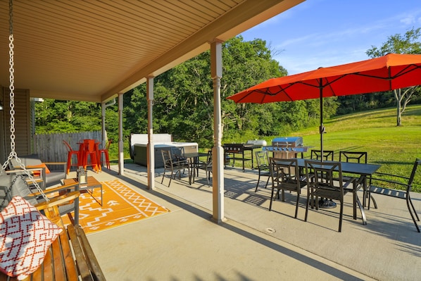 An outdoor patio area with a covered seating area, barbecue grill, and tables with chairs.