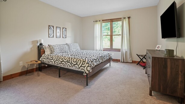 A bedroom with a bed, a desk, a TV, and a window with curtains. - Espolon Ranch | 5BR, Pool, & Pickleball (New Plymouth)