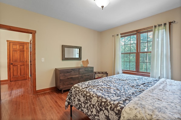 Un dormitorio con una cama grande, cómoda de madera y una ventana con cortinas.