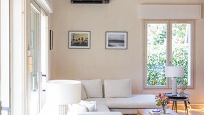 Een woonkamer met een bank, een salontafel, een lamp en twee ingelijste foto’s aan de muur.