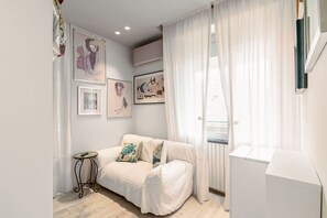 A bedroom with a bed, a small table, and a radiator.