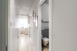 A modern hallway with a toilet, framed pictures, and a light-colored floor.