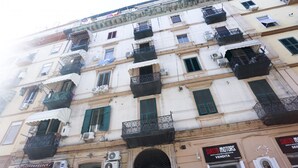 A multi-story building with balconies, air conditioning units, and a storefront with a sign. - GuestHost - Track Station Studio Apartment - with Netflix (Napoli)