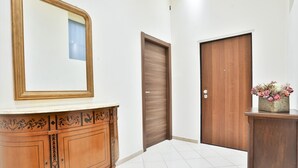 A hallway with a wooden door, a cabinet with a mirror, and a vase with flowers. - GuestHost - Track Station Studio Apartment - with Netflix (Napoli)