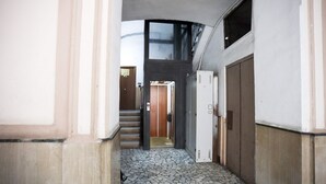 A hallway with a tiled floor, a staircase, and a door leading to an elevator. - GuestHost - Track Station Studio Apartment - with Netflix (Napoli)