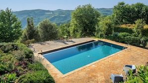 Una piscina rectangular con superficie de agua azul cristalina, rodeada por un patio de ladrillo.