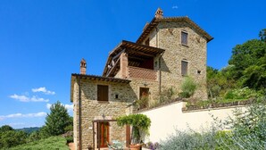 Un edificio de piedra con balcón, una puerta y una maceta.