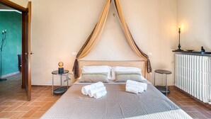 Un dormitorio con cama, mesita de noche, lámpara y radiador.