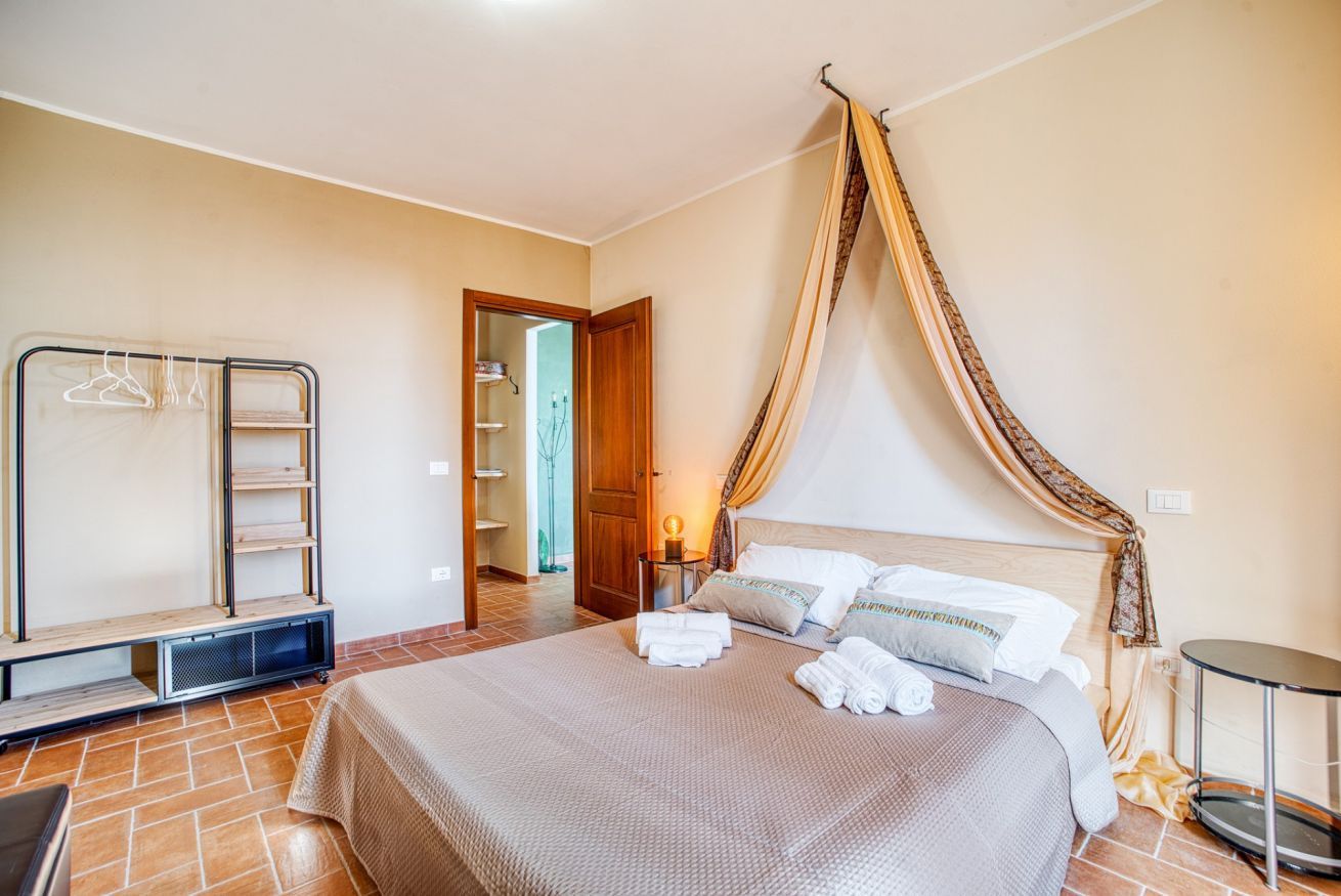 A bedroom with a bed, a wardrobe, a bedside table, and a canopy.