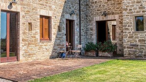 Un edificio de piedra con un patio, mobiliario exterior y un pequeño jardín.