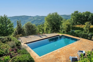 Ein rechteckiger Swimmingpool mit glasklarer, blauer Wasseroberfläche, umgeben von einer Pflasterterrasse.
