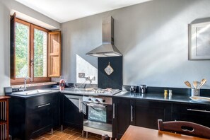 Een koelkast, een oven, een kookplaat, kookgerei, borden en bestek