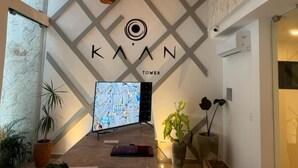 Un interior moderno con una pantalla grande mostrando un mapa, una mesa de recepción y un letrero que dice "KAAN TOWER".