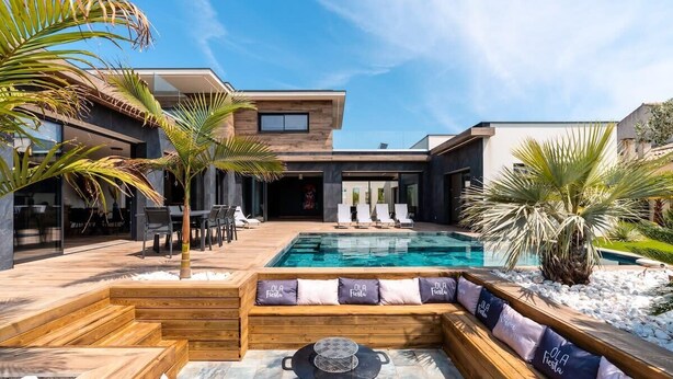 Un espace piscine extérieur moderne, doté d’une terrasse en bois, de chaises longues et d’une table de billard.