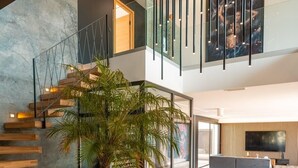 Un intérieur moderne avec un escalier, une grande plante en pot et un téléviseur à écran plat dans un vaste espace de vie.