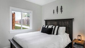 A bedroom with a large bed, a window, and a wall with tree decorations.