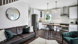 A modern kitchen with white cabinets, a central island, and bar stools.