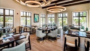 Un restaurante con varias zonas de comedor, amplios ventanales y un diseño de techo moderno.