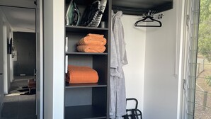 A modern room with a built-in wardrobe, a seating area with a leather chair, and a view through a window. - Luxury new 2 bedrm with ensuites, scenic views & outdoor bath close to winery 🍇 (Mount Alford)
