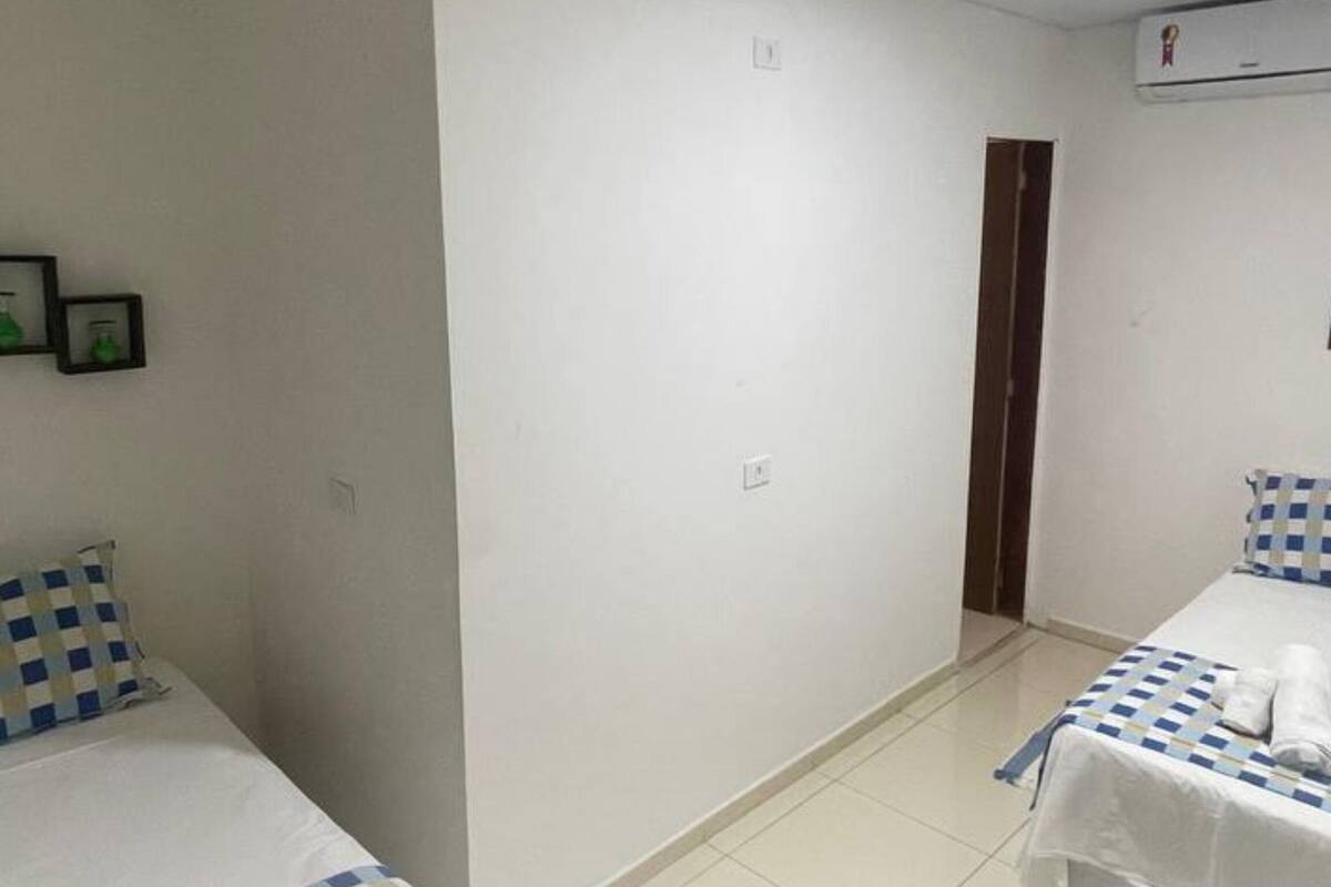 Ein Hotelzimmer mit zwei Betten, einem weiß gefliesten Boden und einer Tür zu einem anderen Raum.