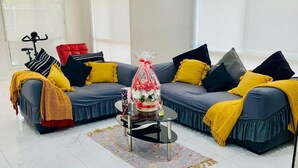 Een moderne woonkamer met een hoekbank, een klein rond tafeltje en een kamerplant.