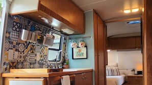 Cozinha compacta para motorhome, com fogão, pia e armários de madeira.