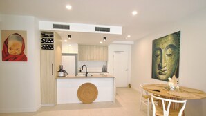 A modern kitchen with a central island, white cabinetry, and a dining area with a round table and chairs. - UNIT 20707 1bed Unit (Sunshine Coast)